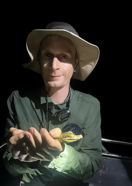 Joe holiding a baby caiman in the Amazon Rainforest