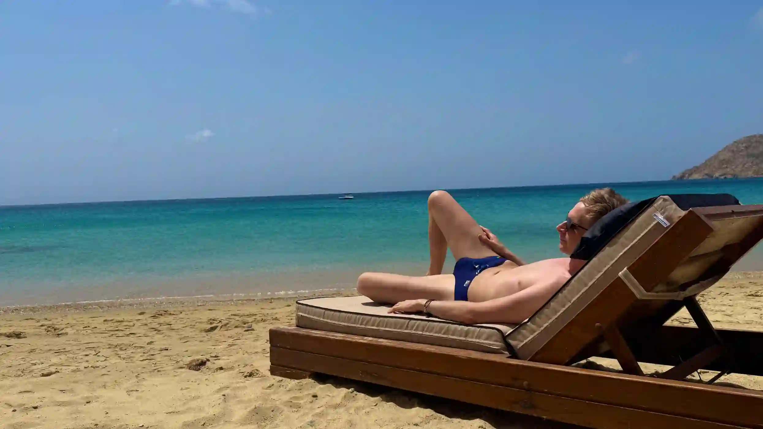Joe relaxing on a beach lounger looking out into the crystal clear waters of the sea.